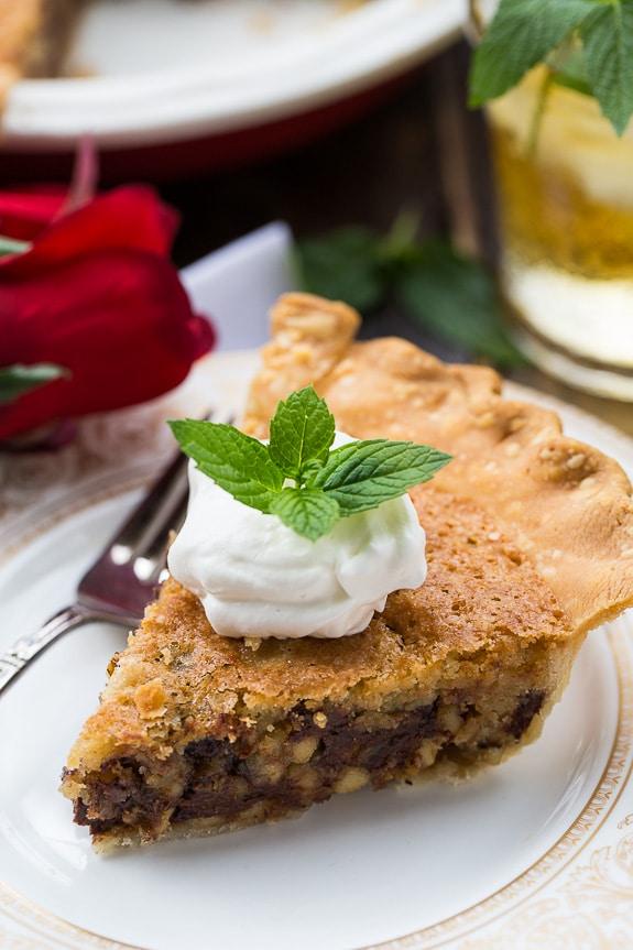 Kentucky Derby Pie with a gooey chocolate and walnut filling. Top with bourbon whipped cream for a delicious southern dessert.
