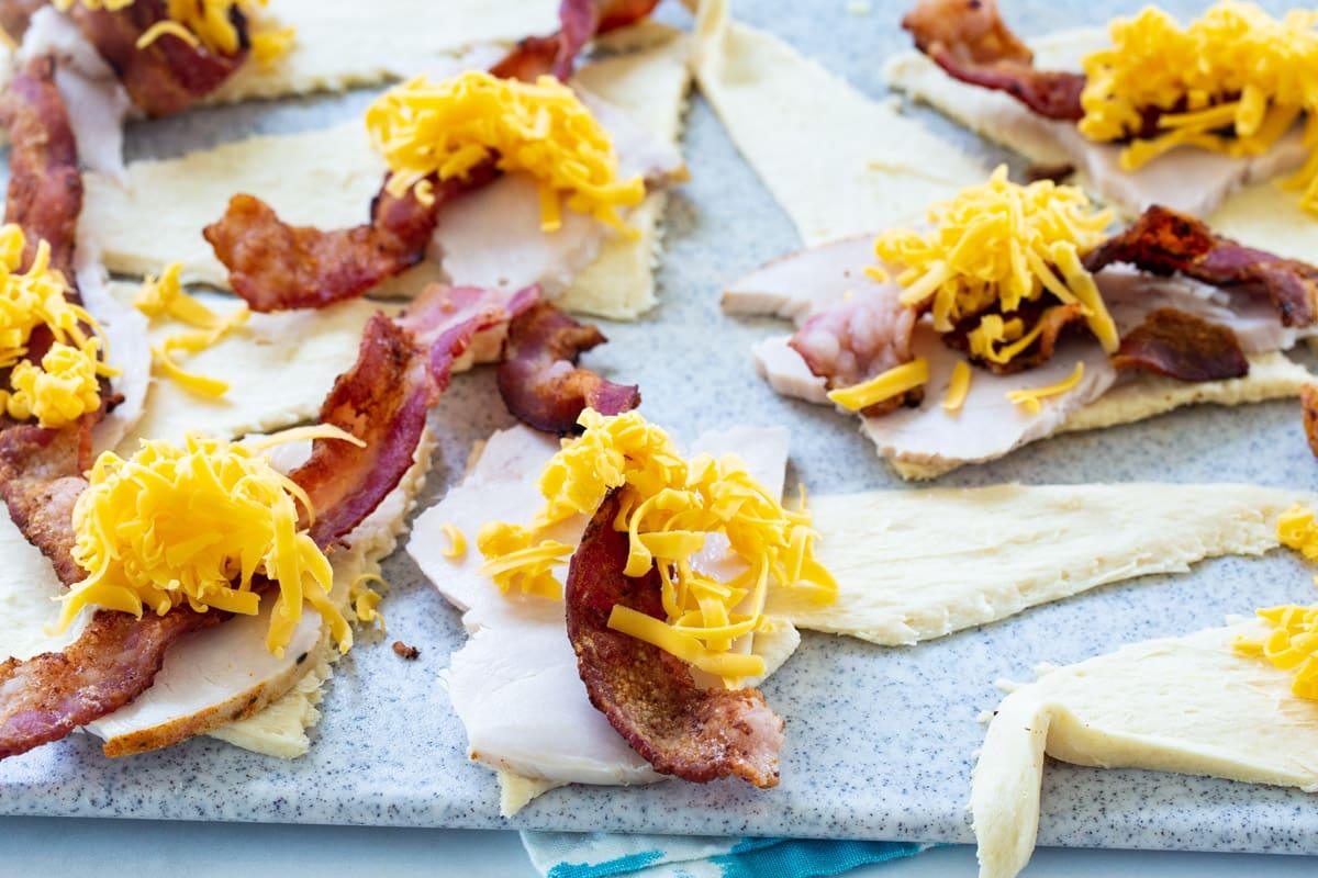 Turkey, bacon and cheese piled on pieces of crescent dough.