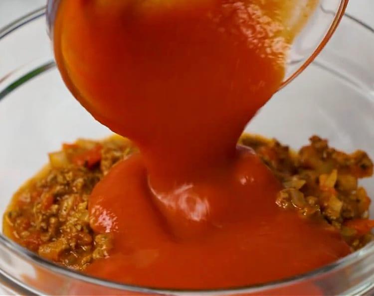 Adding tomato sauce to ground beef mixture.
