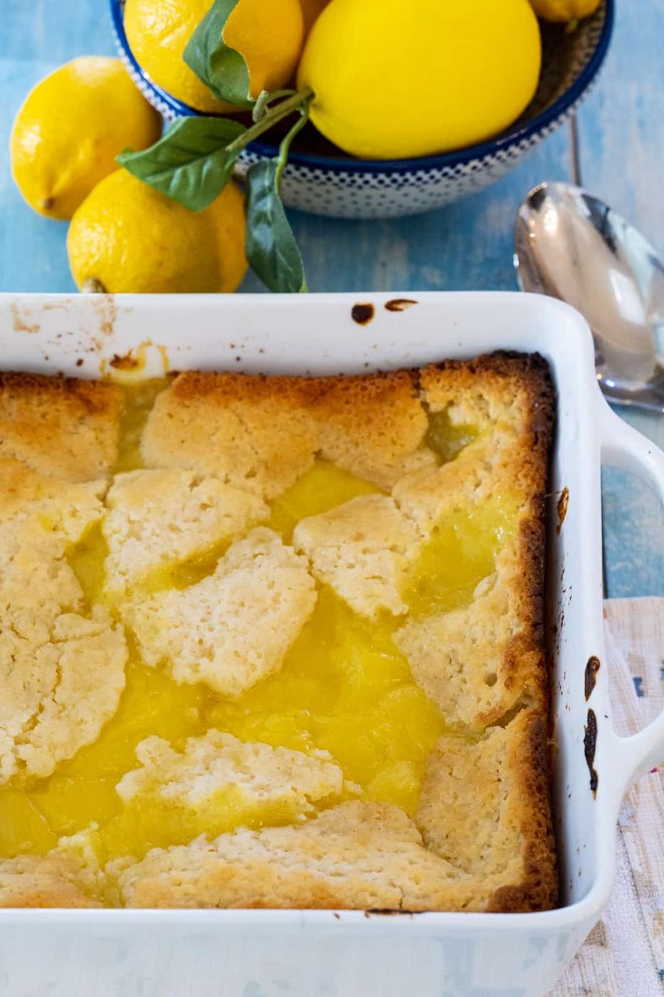 Lemon Cobbler in a baking dish and bowl full of lemons.
