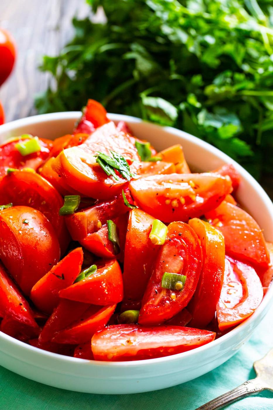 Marinated Tomatoes in a bowl and a bunch of fresh parsley.
