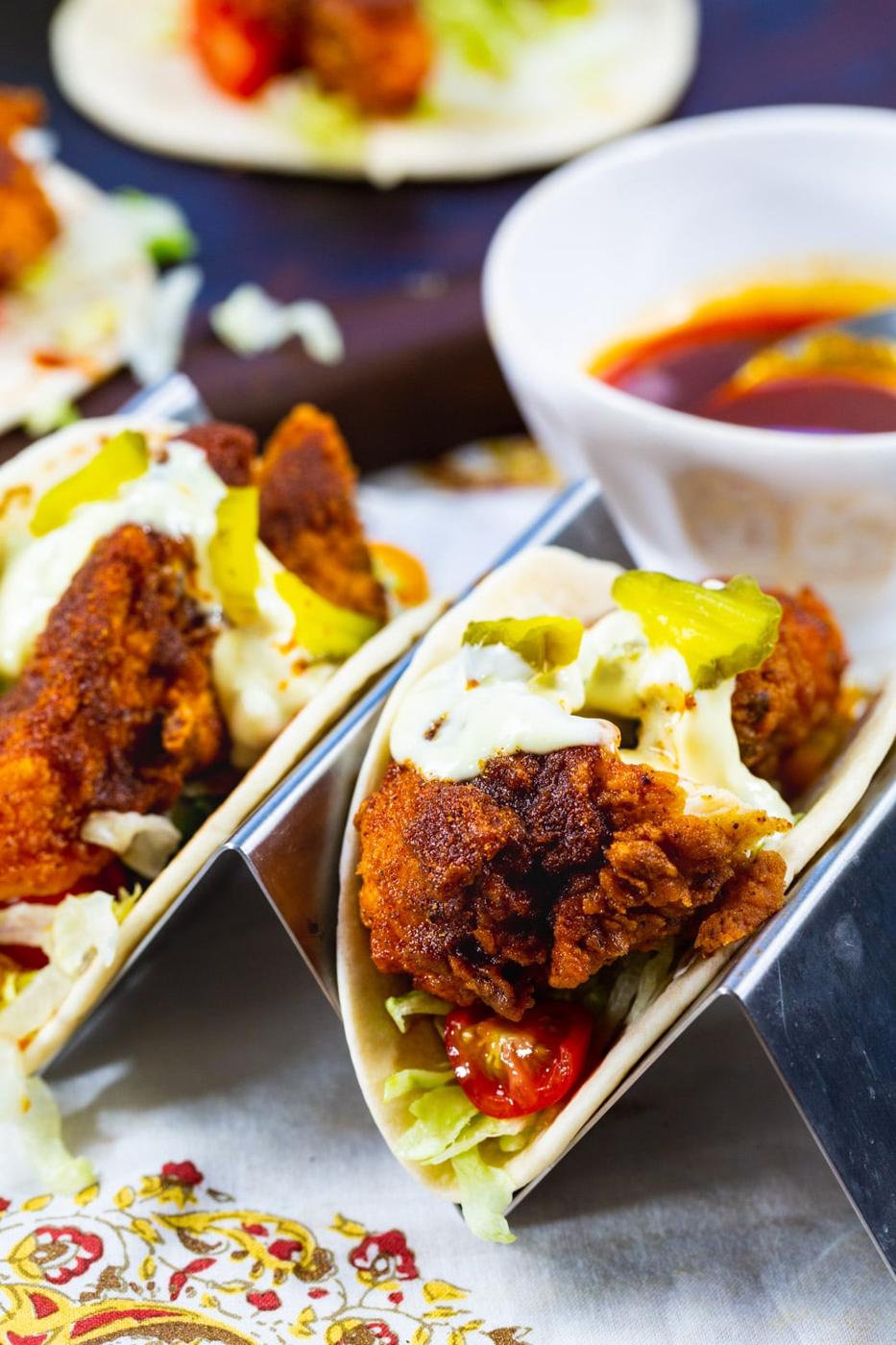 Fried Chicken Tacos with hot sauce topped with dill pickles.