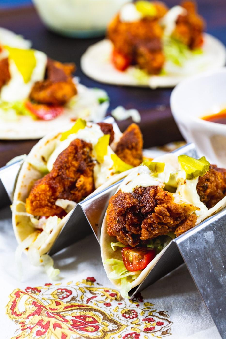 Two Nashville Hot Chicken Tacos in a tray with more in background.