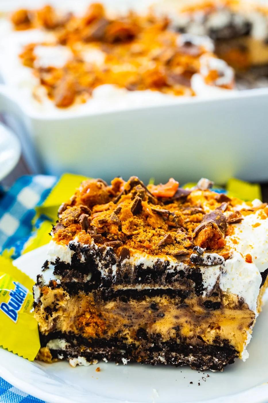 Slice of icebox cake on plate with the rest of cake in a baking dish in background.