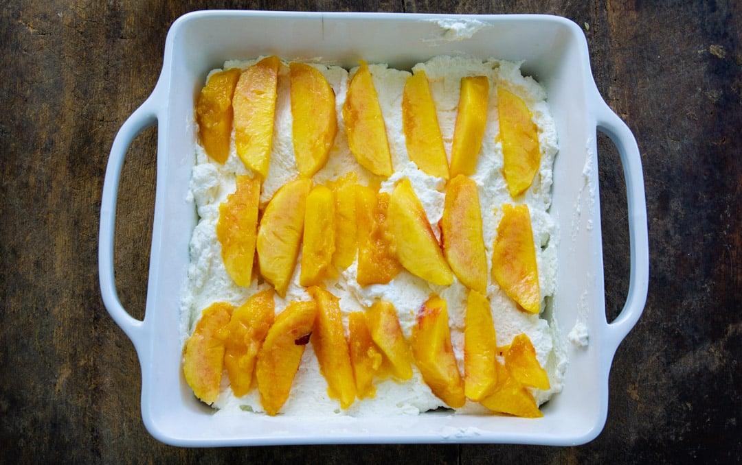 Cream cheese spread on top of graham crackers and topped with peach slices.
