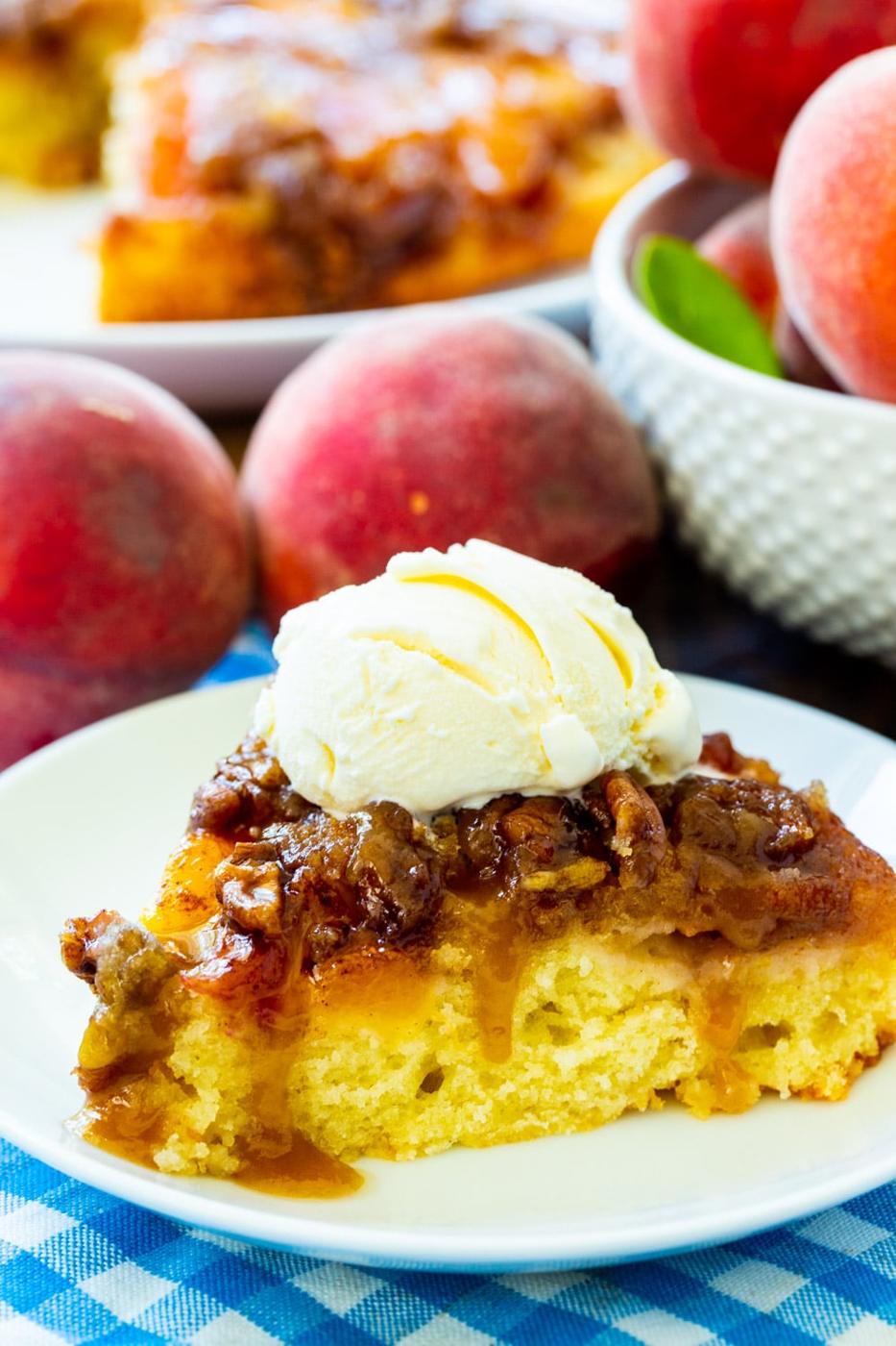 Peach Praline Upside Down Cake slice on a plate surrounded by fresh peaches.
