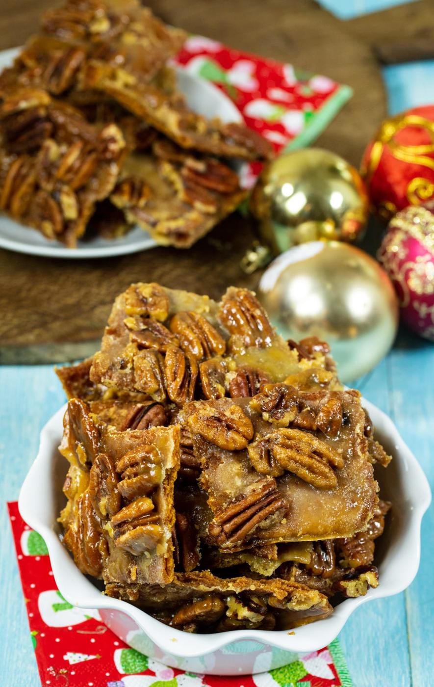 Pieces of Pecan Bark in serving dish and ornaments in background.