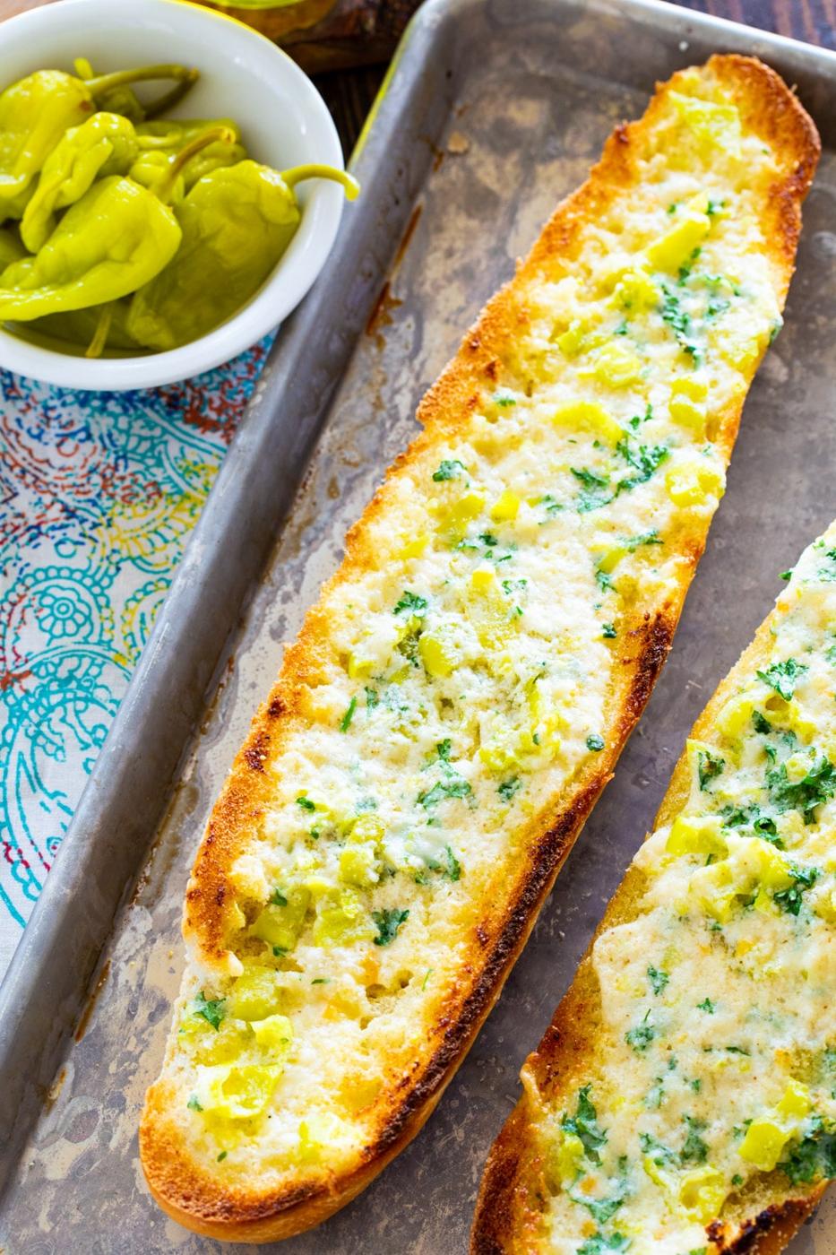 Whole loaf of garlic bread with bowl of peppers.