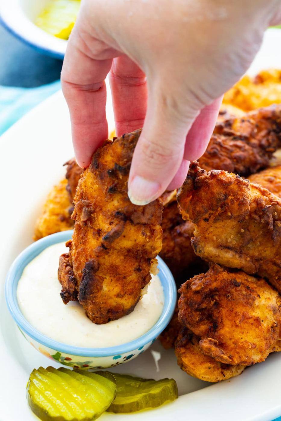 Pickle-Brined Chicken Tenders on plate with small bowl of dipping sauce and pickle slices.