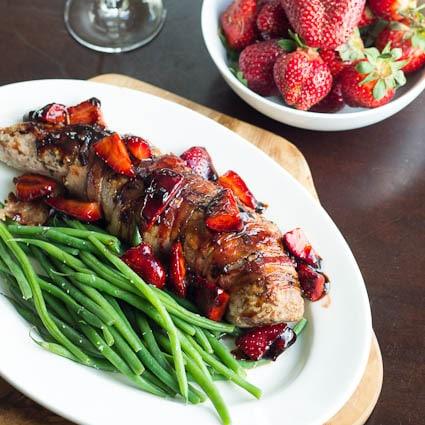 Pork Tenderloin with Balsamic Strawberries on a platter and a bowl of strawberries.
