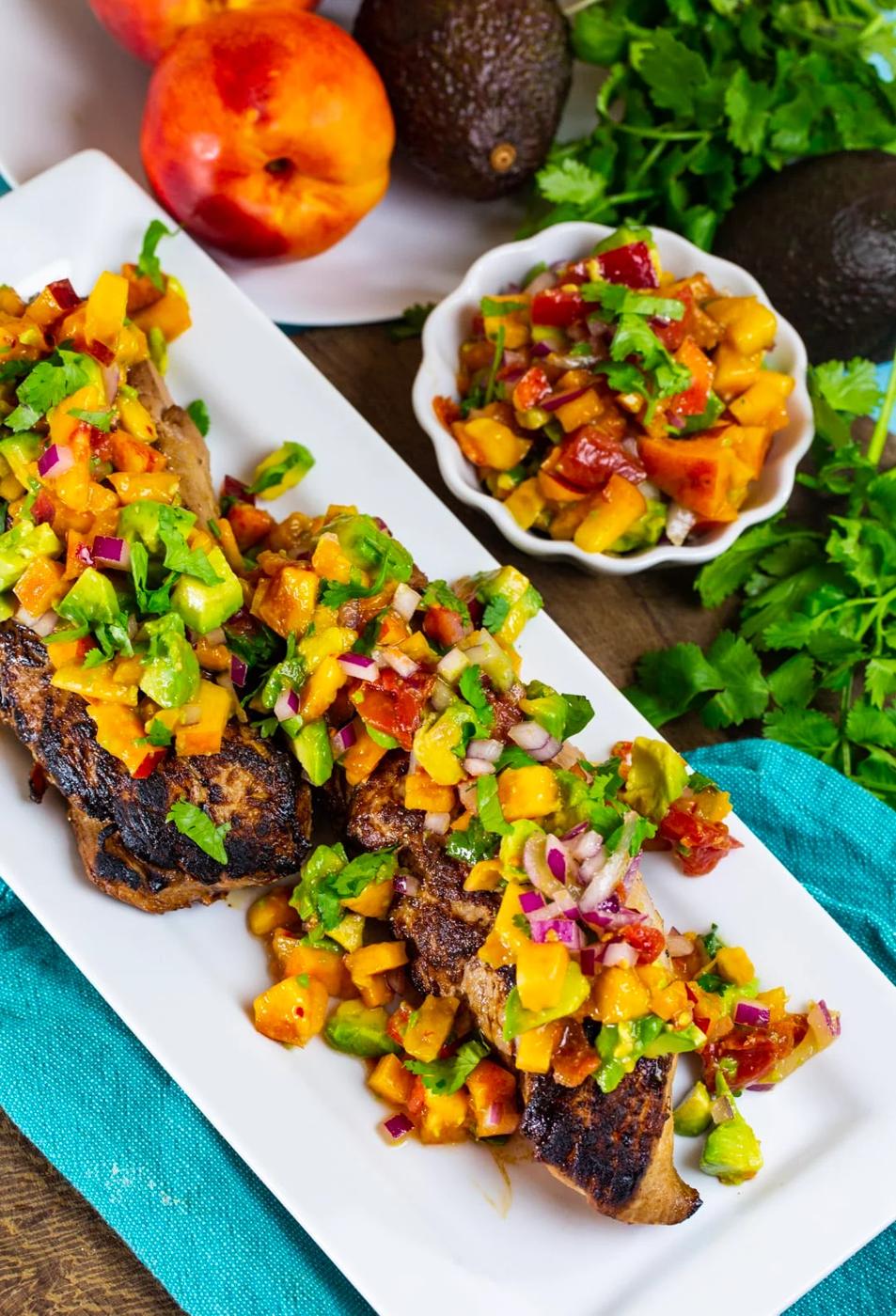 Cooked pork tenderloin covered in salsa and a bowl full of salsa.