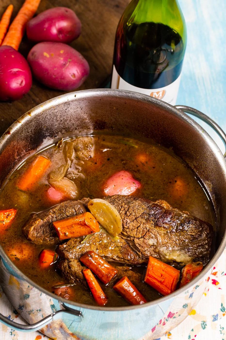 Finished dish in a Dutch oven and bottle of wine.