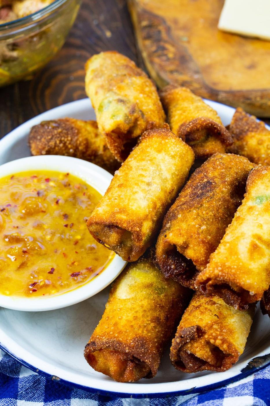 Pulled Pork Egg Rolls in serving tray with bowl of dipping sauce.