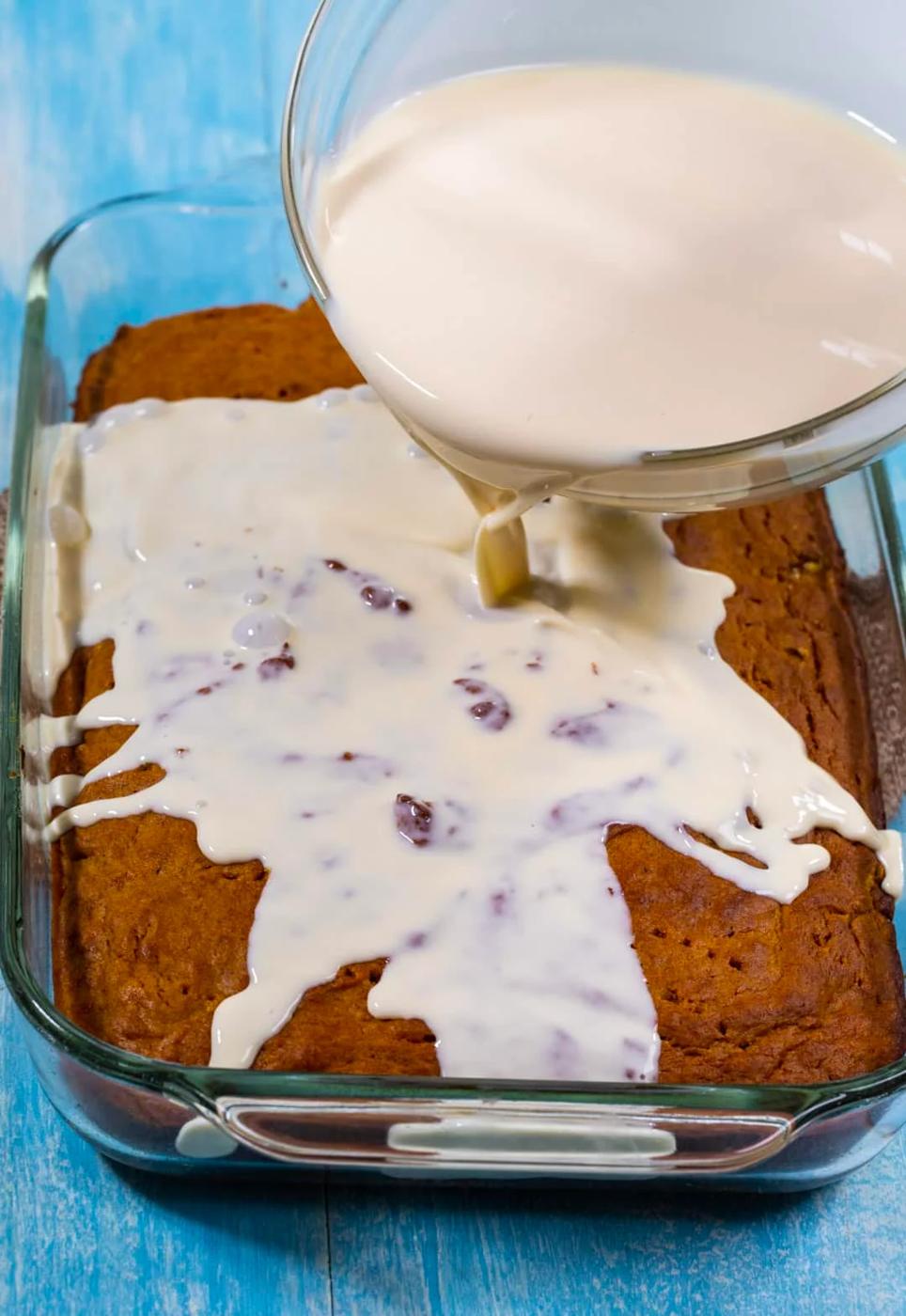 Pouring milk mixture over cake.