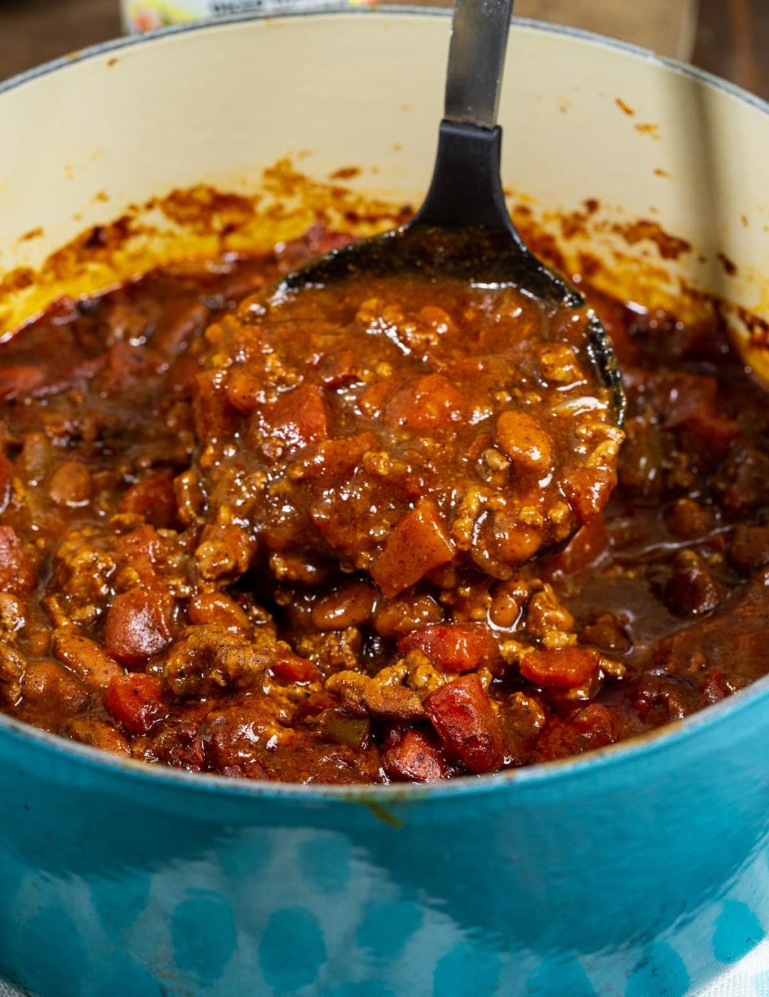 Ladle scooping up chili.