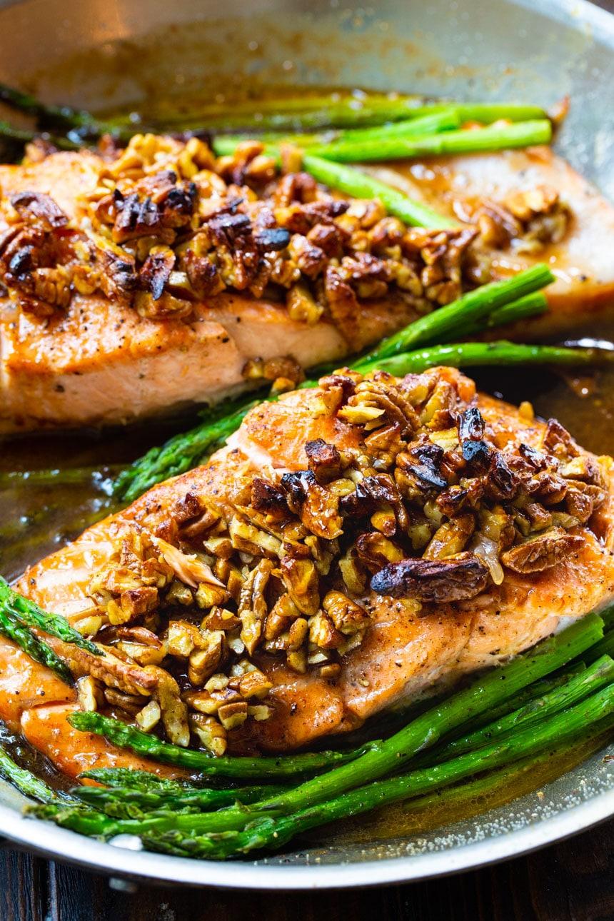 Bourbon Pecan Glazed Salmon fillets in a pan with asparagus