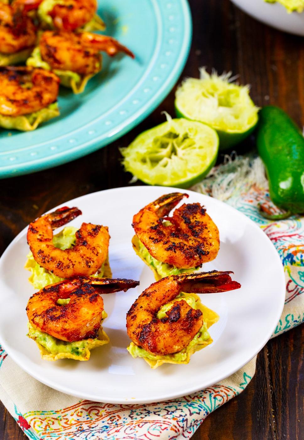 Tostada Bites topped with shrimp on a plate with lime halves.