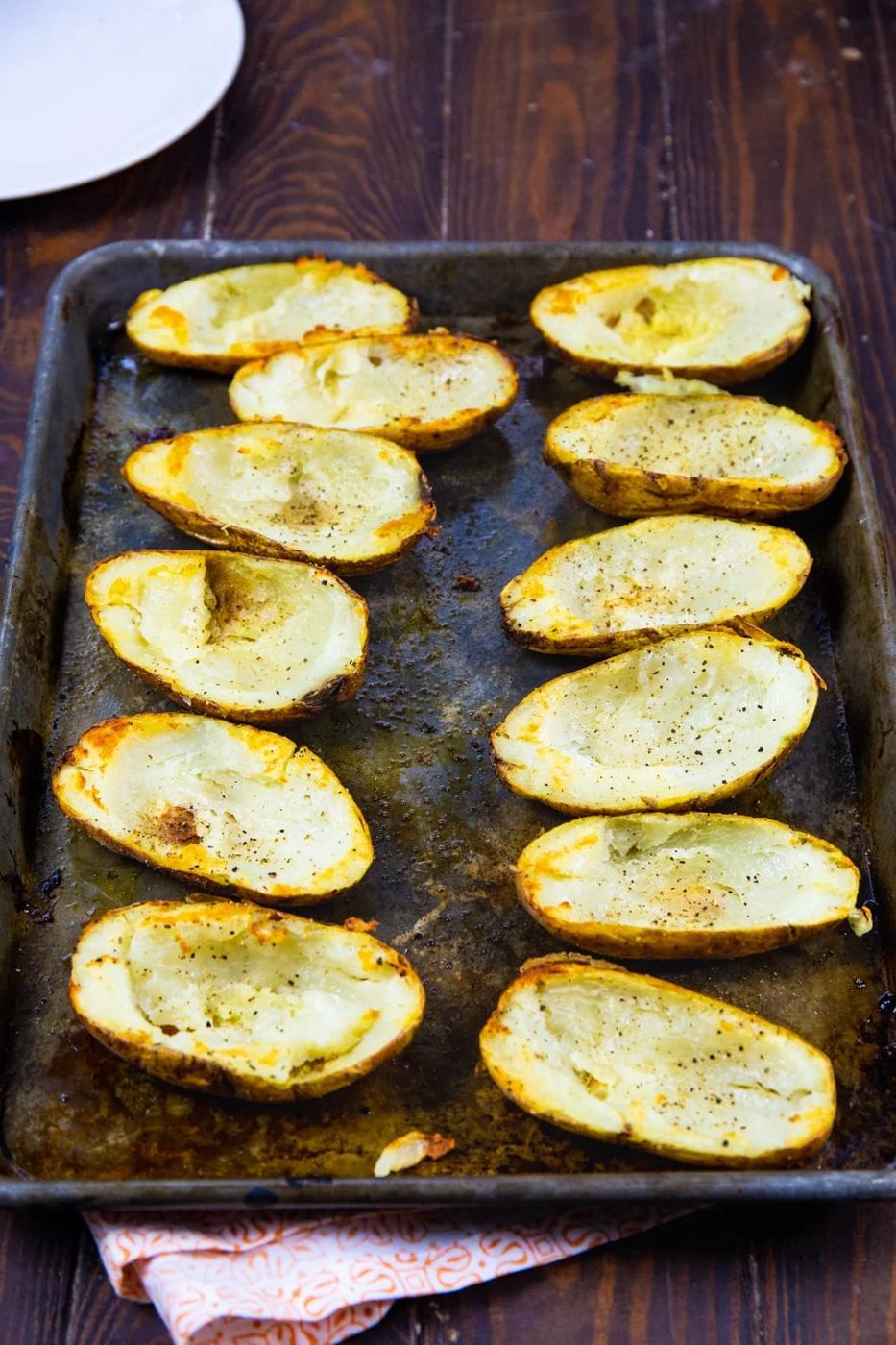 Hollowed out potato halves on baking sheet.