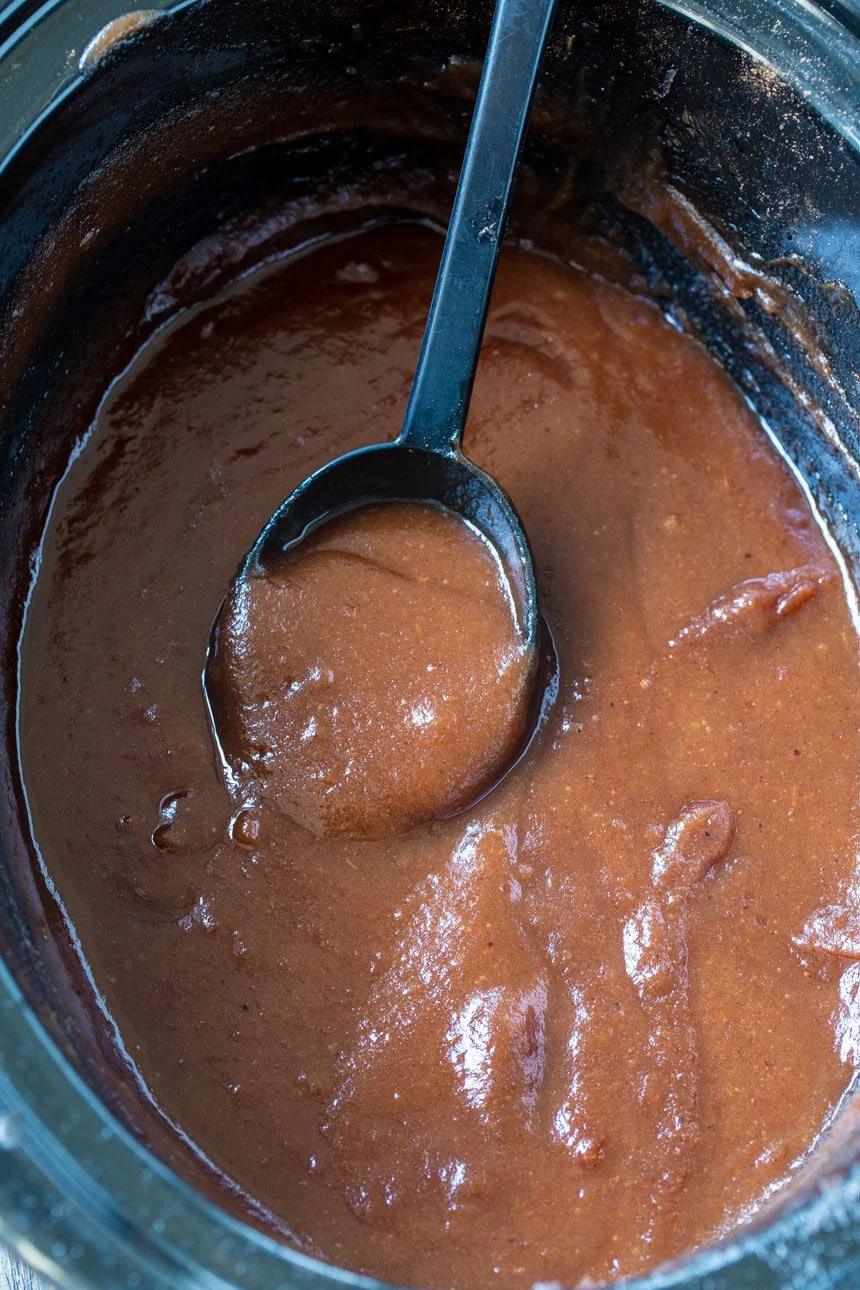 Apple Butter in slow cooker with spoon scooping it.