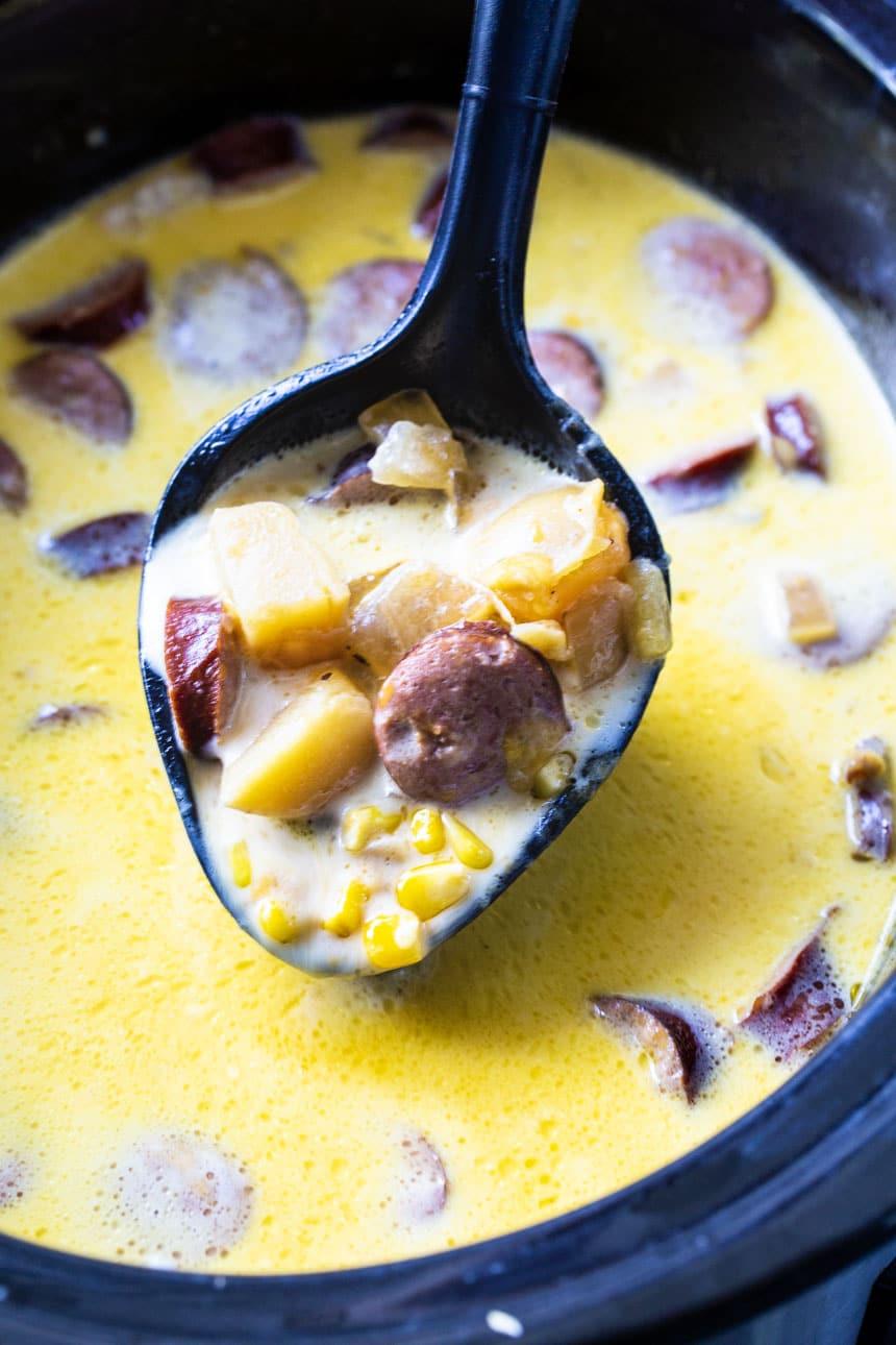 Spoon scooping chowder out of slow cooker.