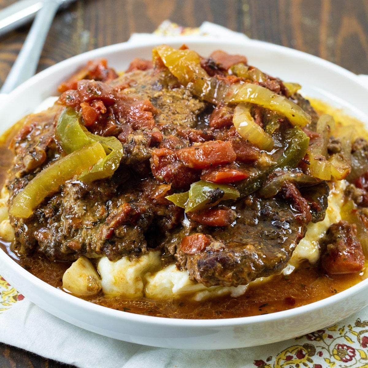 Slow Cooker Swiss Steak over mashed potatoes on a plate.