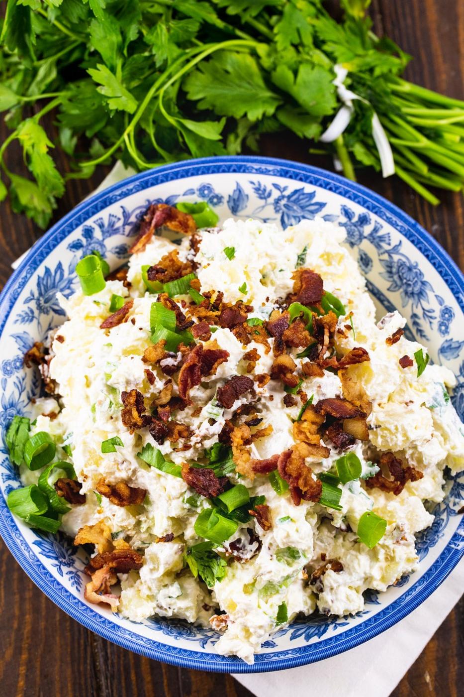 Overhead of potato salad in blue and white bowl with parlsey next to it.