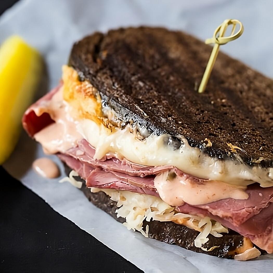 Spicy Reuben sandwich on piece of parchment paper.
