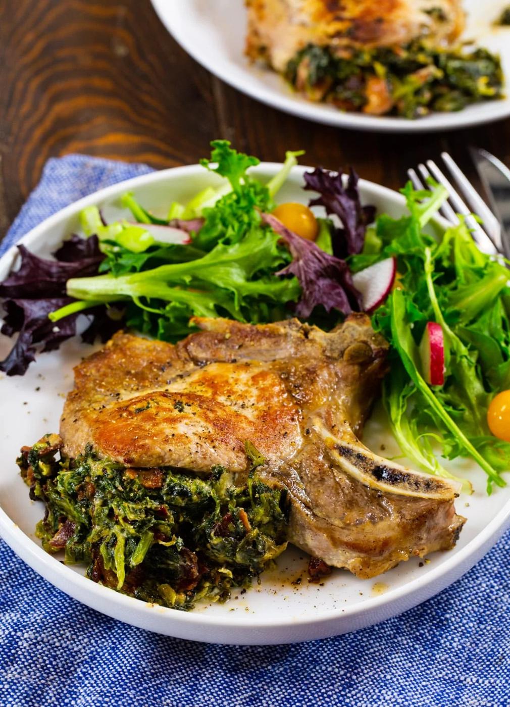 Spinach and Bacon Stuffed Pork Chop on plate with salad.