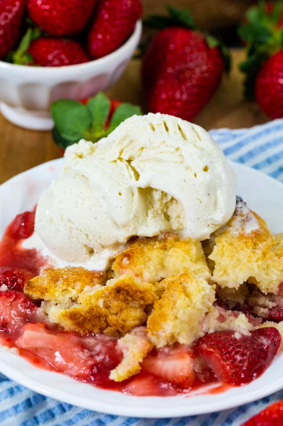 Strawberry Cobbler topped with vanilla ice cream on a plate.