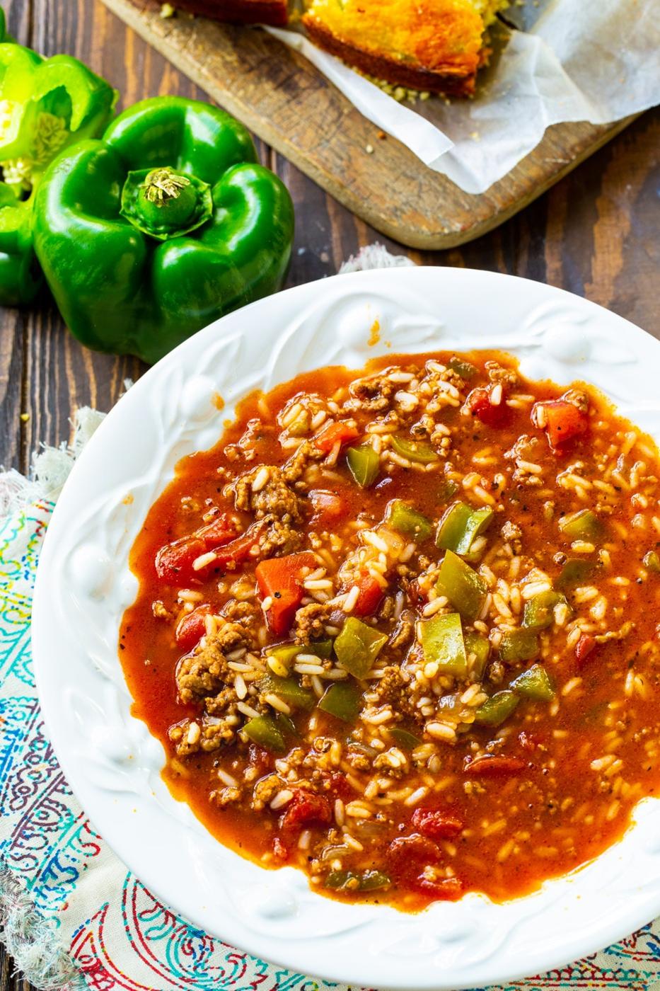 Bowl full of Stuffed Pepper Soup with green peppers next to it.