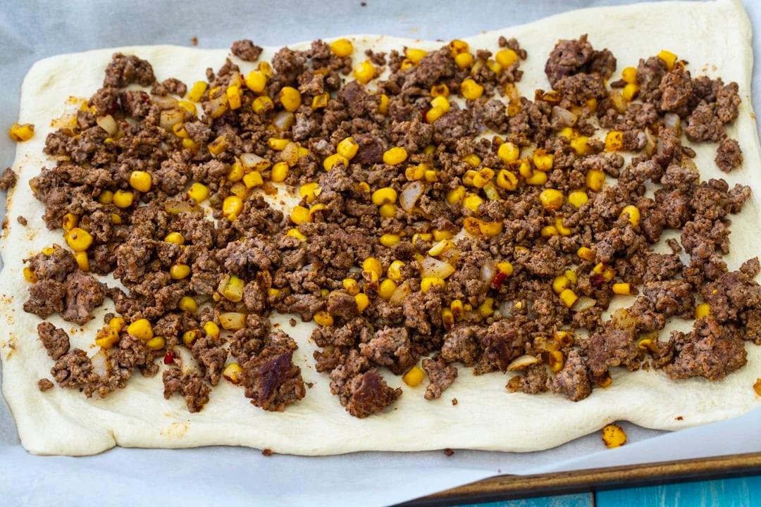 Taco filling spread on pizza dough.