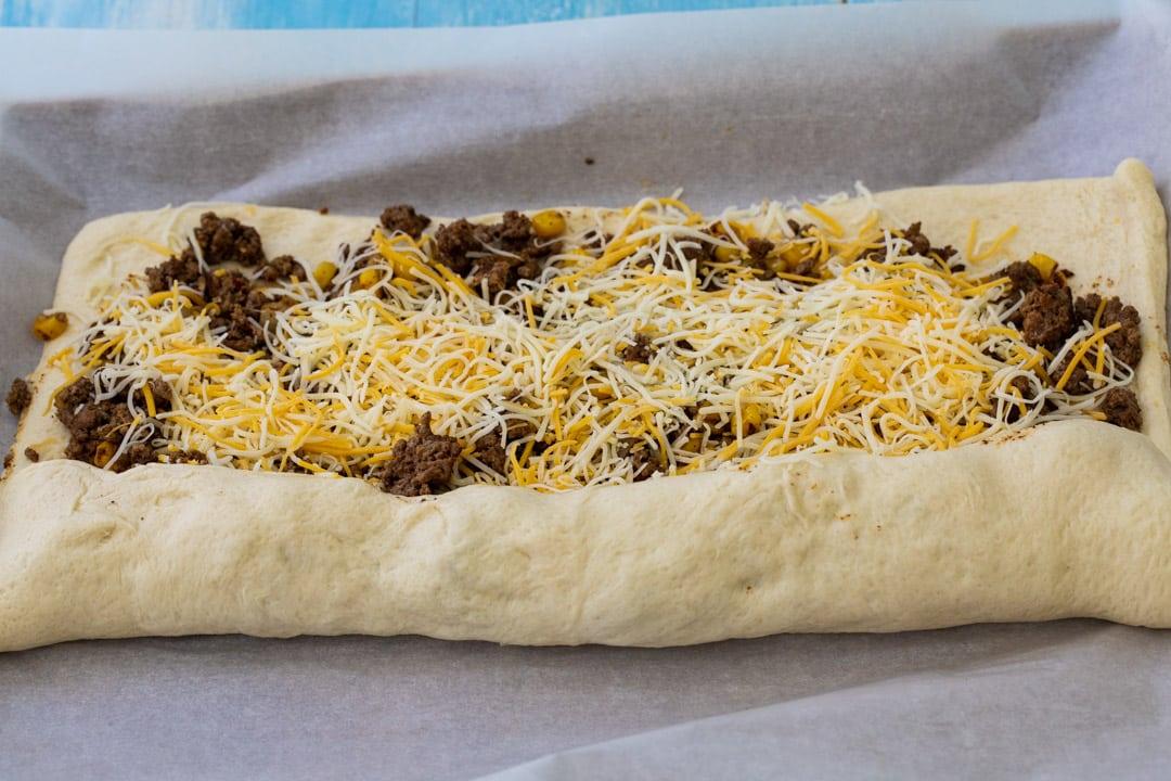 Pizza dough being rolled up.
