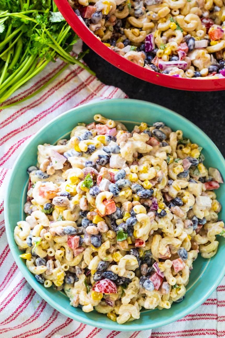 Overhead of Texas Caviar Pasta Salad in a blue bowl on a red striped kitchen towel.