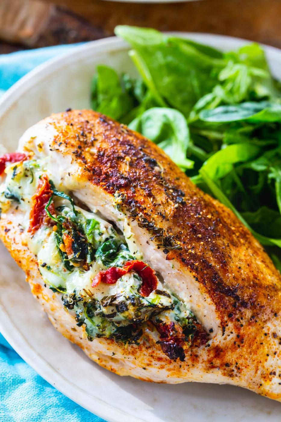Piece of Tuscan Stuffed Chicken on plate with green salad.