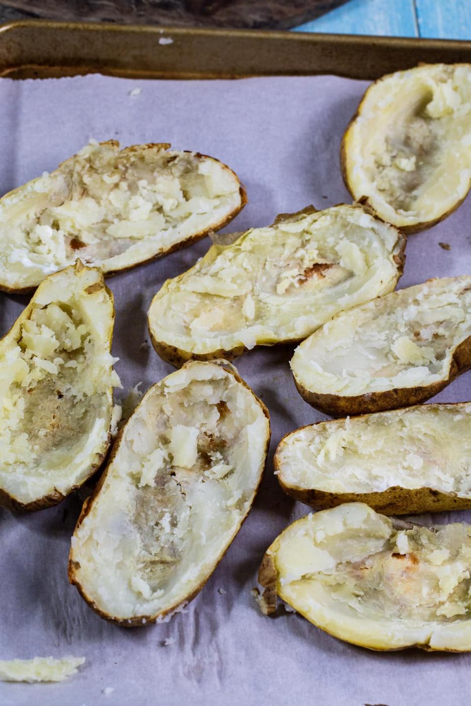Hollowed out potato halves on baking sheet.