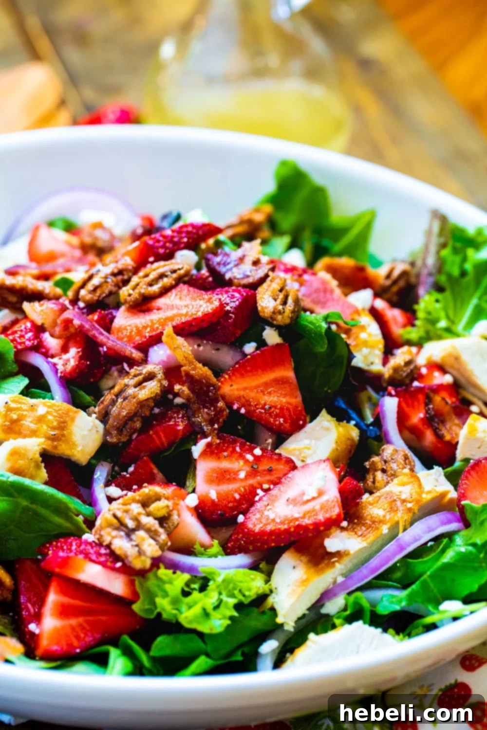 Close-up of Strawberry Fields Salad in a bowl, highlighting feta, bacon, and glazed pecans.