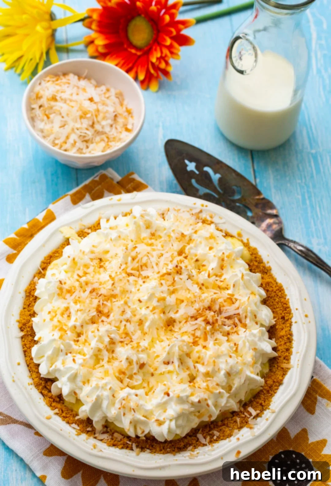 Close-up of a whole Coconut Cream Pie, showing its golden crust, creamy filling, and fluffy whipped cream topping with toasted coconut.