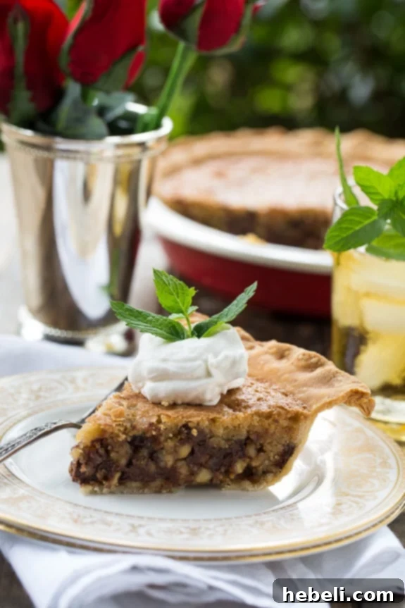 Slice of homemade Kentucky Derby Pie showing its gooey chocolate and walnut filling, perfectly complemented by bourbon whipped cream.