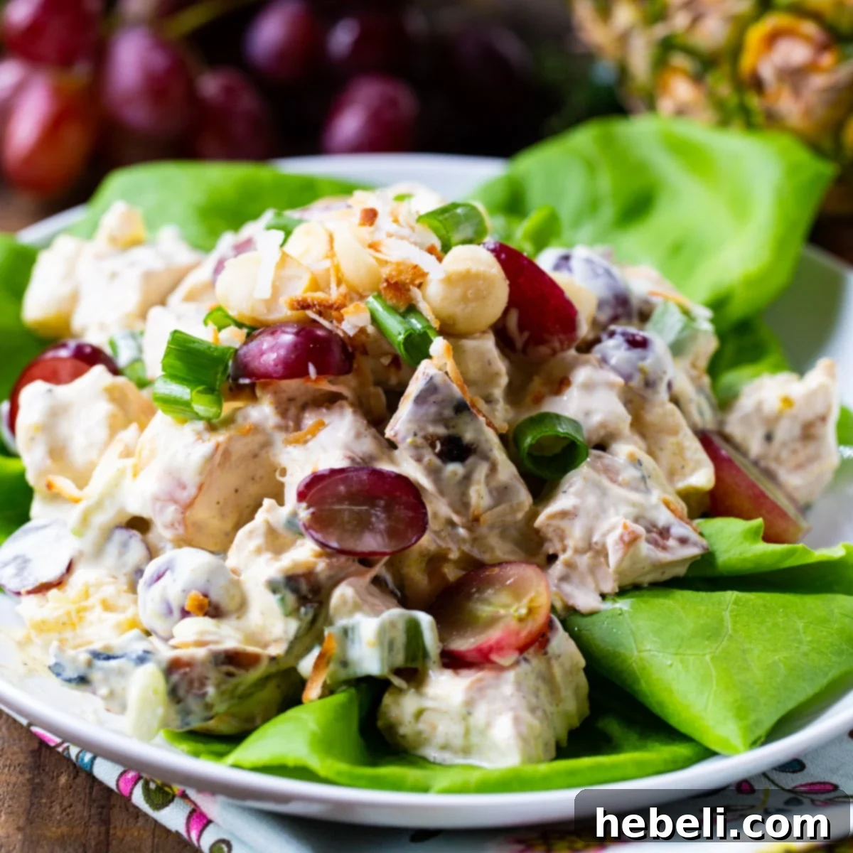 Island Chicken Salad 2 A vibrant bowl of Tropical Chicken Salad on a fresh bed of lettuce, garnished with parsley.