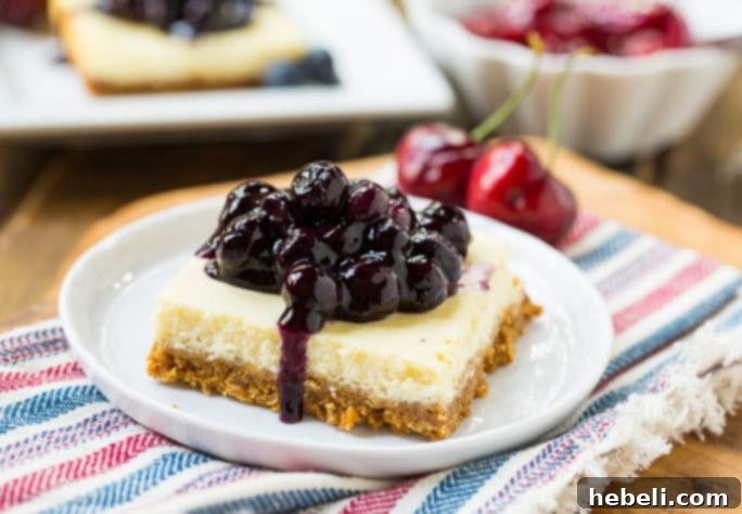 Assorted Lightened-Up Cheesecake Bars presented on a platter, some topped with luscious blueberry sauce, others with sweet cherry topping.