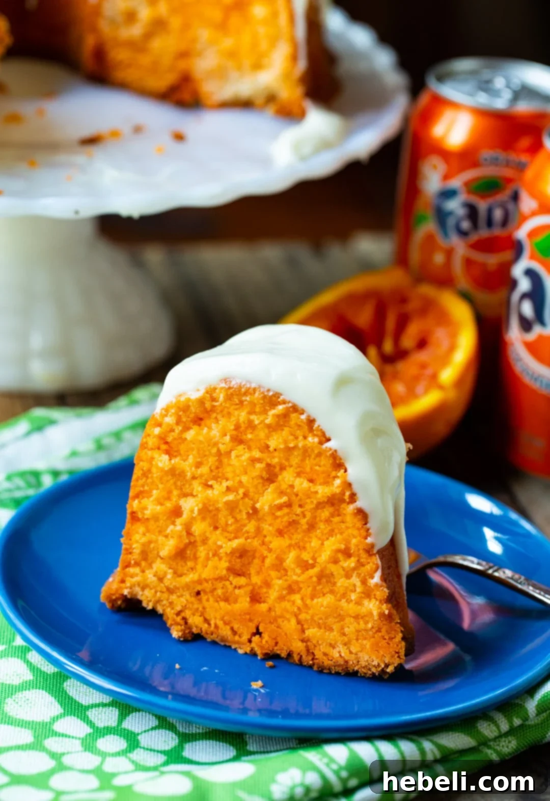 Slice of pound cake on a blue plate with cans of Fanta in the background, hinting at the key ingredient.