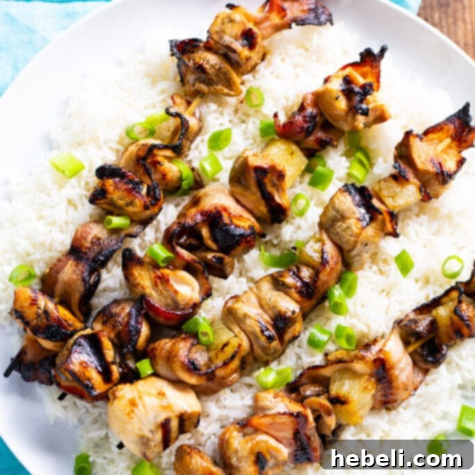 Grilled Chicken and Bacon Skewers 2 Grilled Chicken and Bacon Kabobs served over a bed of fluffy white rice, showcasing the golden-brown chicken, crispy bacon, and vibrant pineapple chunks.