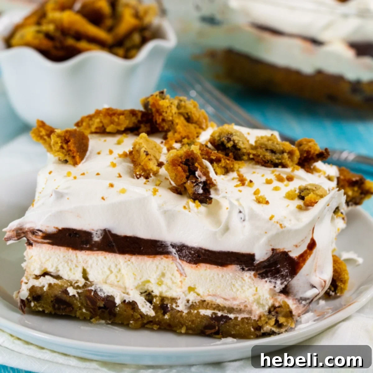 A perfectly portioned square of Chocolate Chip Cookie Delight on a small white plate, showcasing its distinct layers.