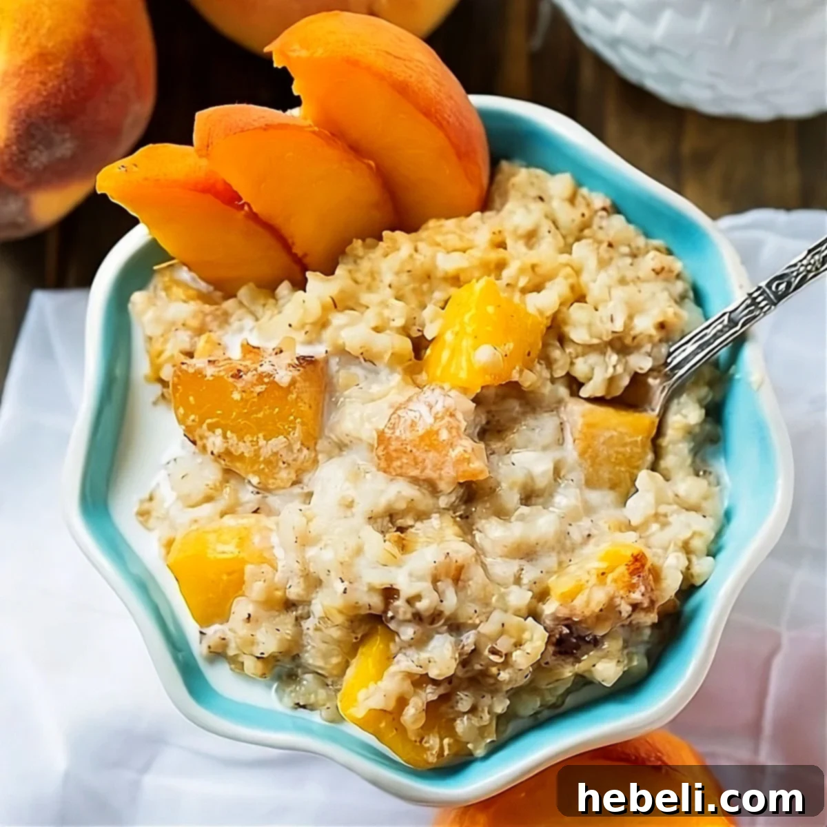 Creamy Slow Cooker Peach Oatmeal 2 A steaming bowl of Crock Pot Peaches and Cream Oatmeal with fresh peach slices and a spoon, ready to be enjoyed.