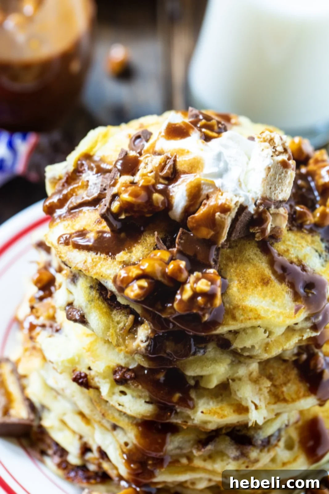 Stack of Snickers Pancakes topped with whipped cream.