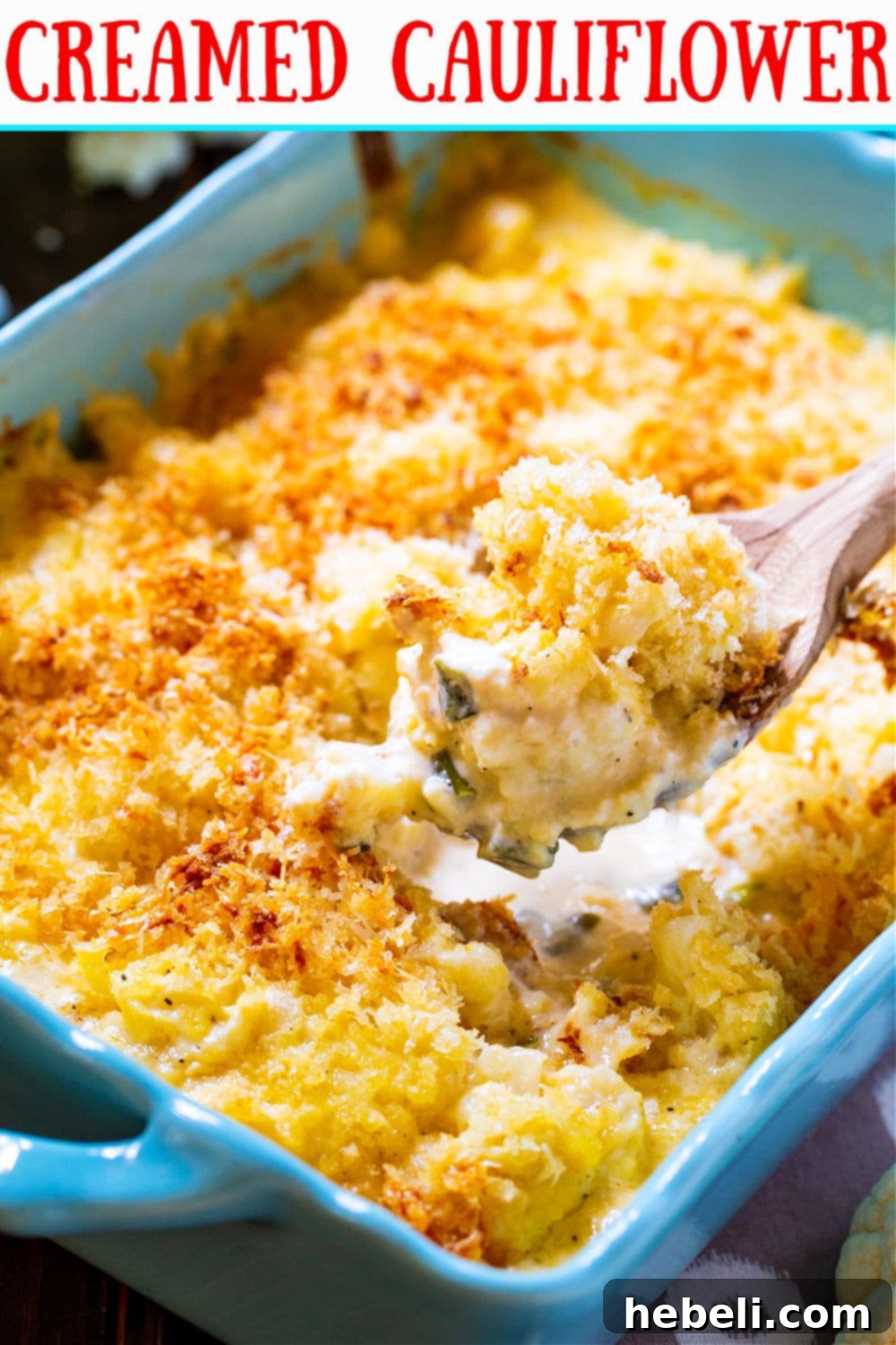 Velvety Cauliflower Mash 4 A spoon scooping a generous portion of Creamed Cauliflower from the baking dish, highlighting its creamy, cheesy texture.