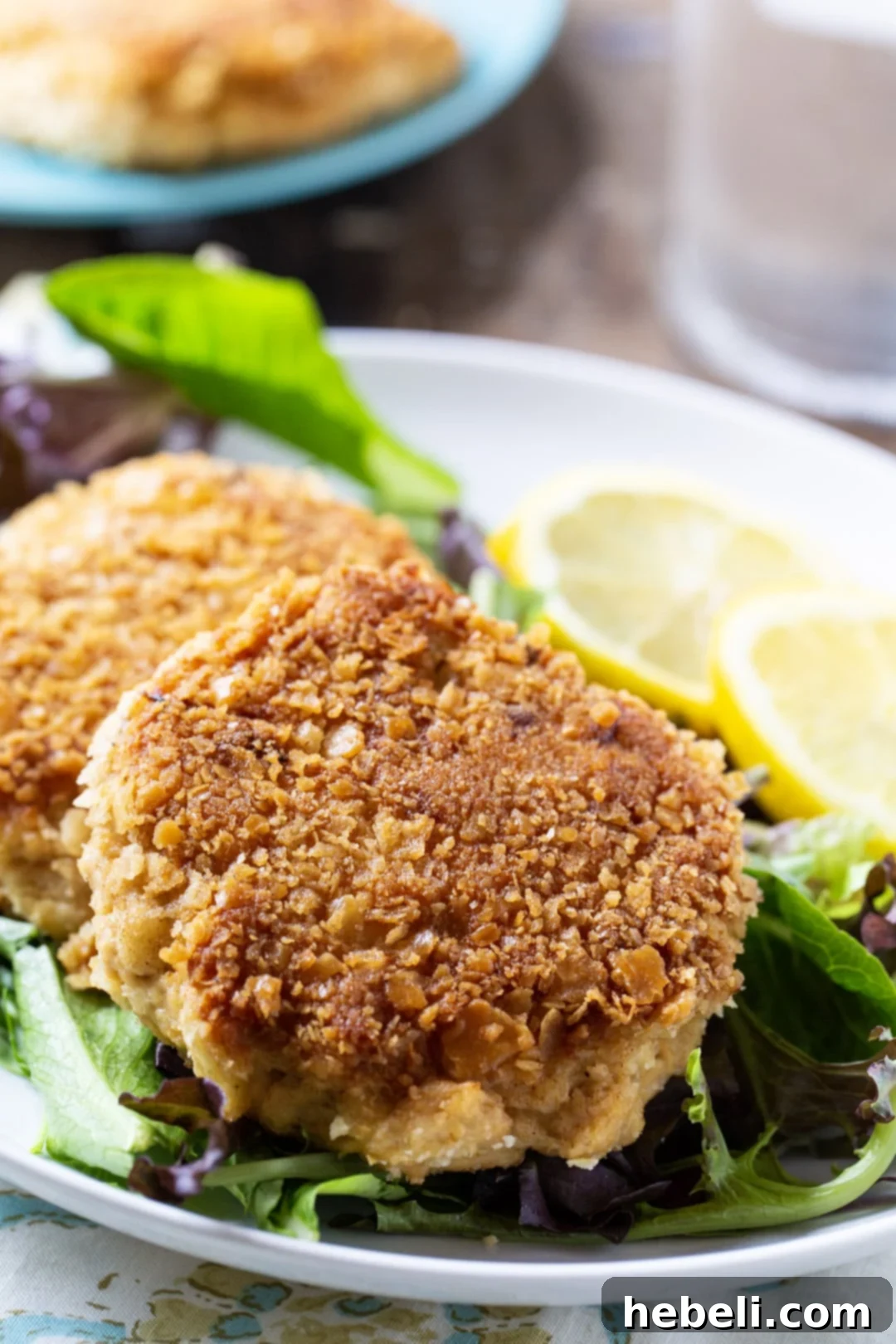 Classic Southern Salmon Cakes 3 Close-up of crispy Southern Salmon Patties garnished with lemon slices and fresh herbs.