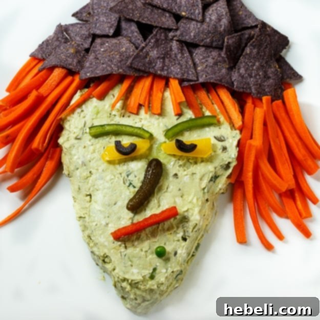 Witch's Brew Guacamole 2 Witch Guacamole Dip, a creamy green dip shaped like a witch's face with vegetable features, perfect for Halloween.