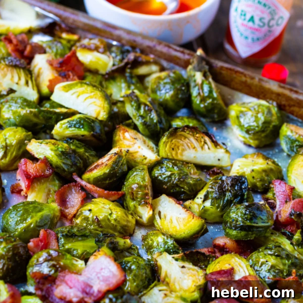 Crispy Roasted Brussels Sprouts with Bacon and TABASCO Honey Glaze on a baking sheet, ready for serving.