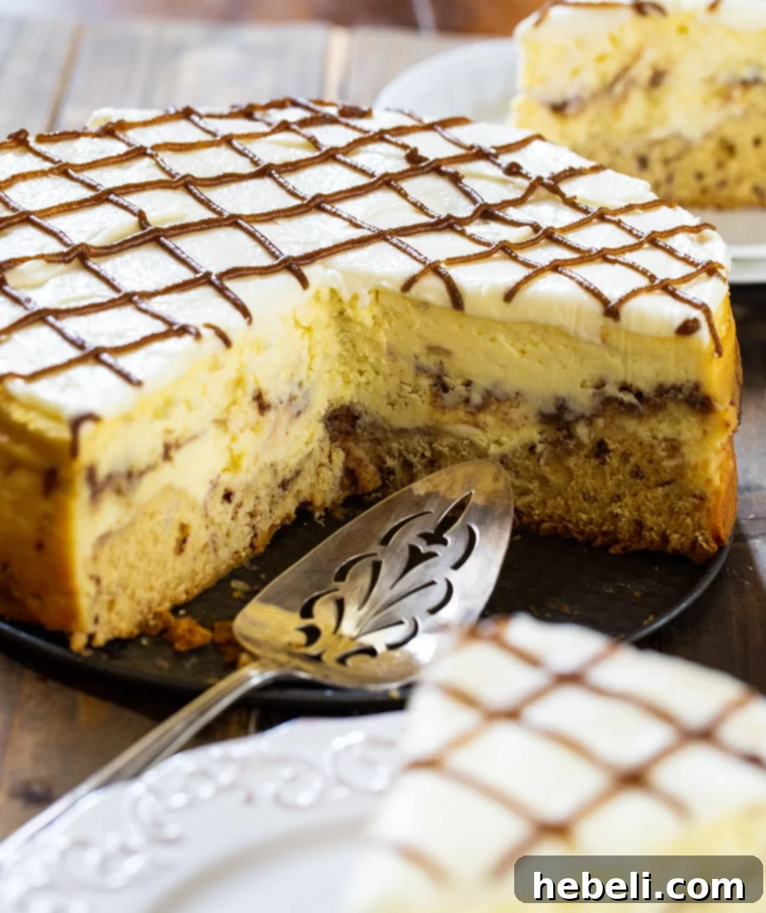 Cinnamon Swirl Cheesecake 3 A baked Cinnamon Roll Cheesecake with several slices already removed, revealing the intricate layers of the cinnamon roll crust, creamy cheesecake filling, and sweet toppings.